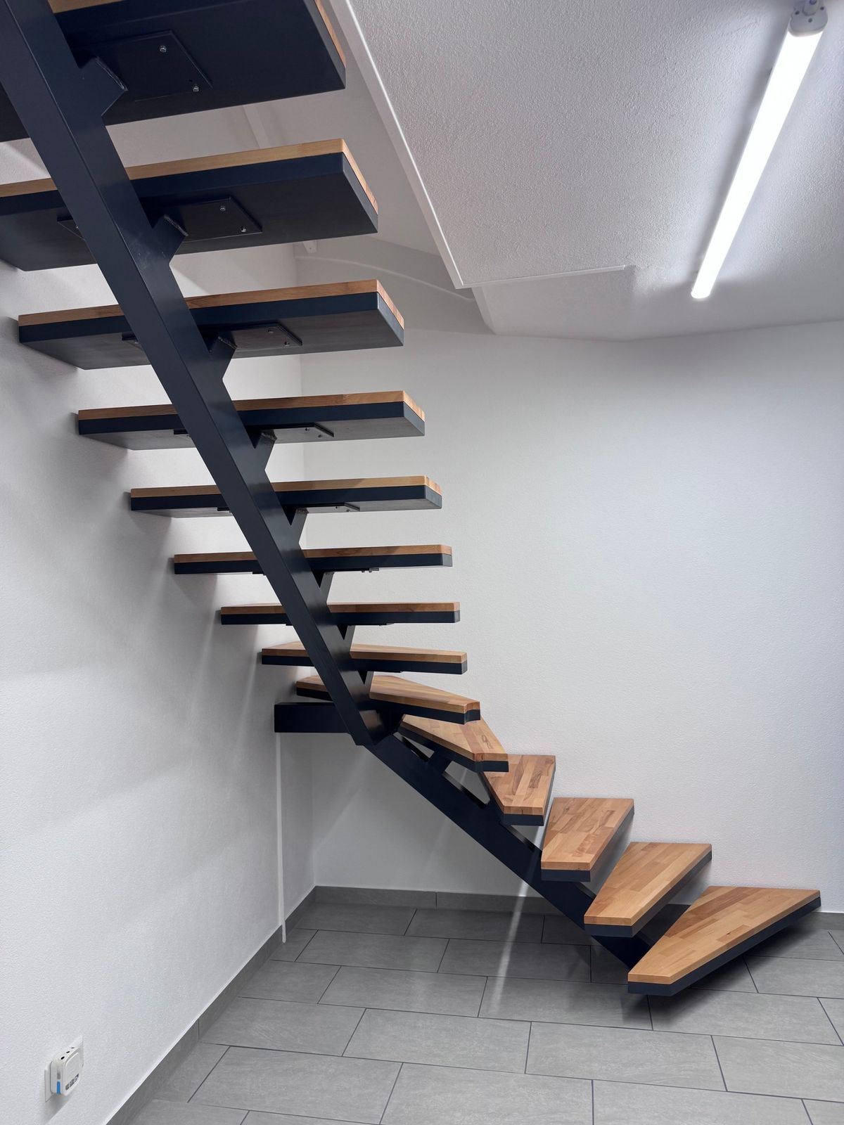Treppe nachher: Stahlwangentreppe mit Holzstufen vor weißer Wand